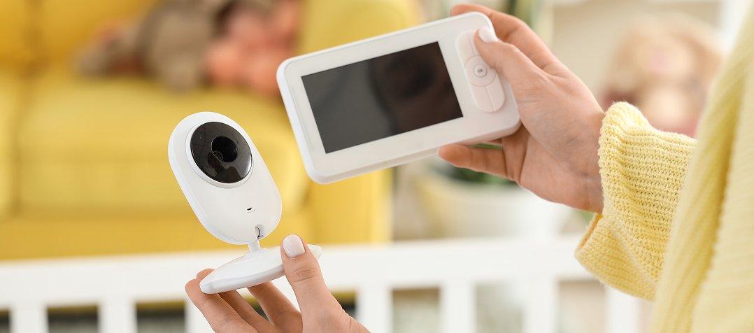 a woman holding a baby monitor and a small camera