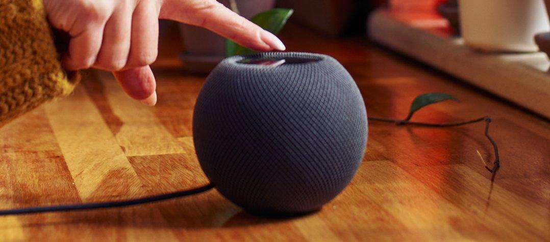 a person touching a small speaker on a wooden floor