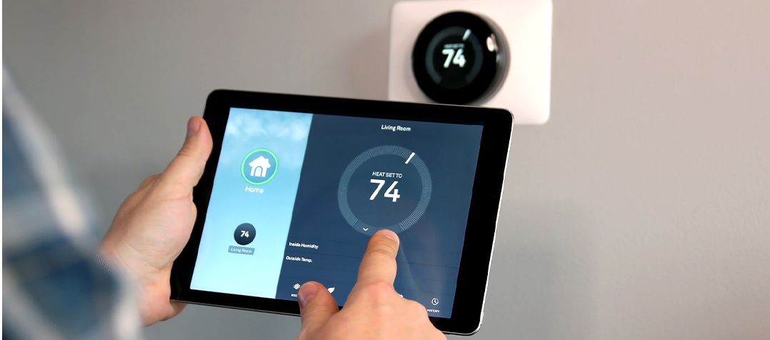 a person holding a tablet with a thermostat on it