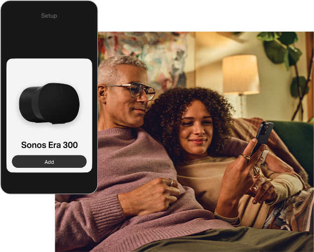 A couple sitting together looking at a mobile phone, with a mobile phone overlaid on top with the Sonos app on the screen