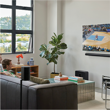 A living room with a sofa, coffee table and a TV on the wall with a soundbar underneath it