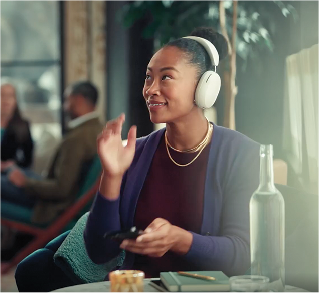 A woman sitting in a cafe with white over-ear headphones on