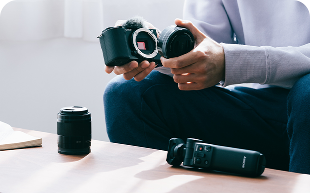 A person putting a lens onto a camera