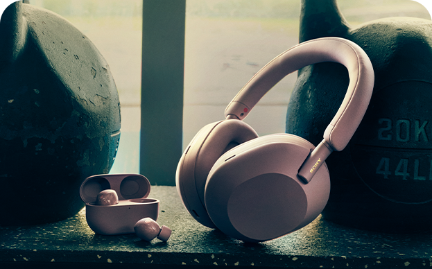 A pair of over-ear headphones next to some earbuds