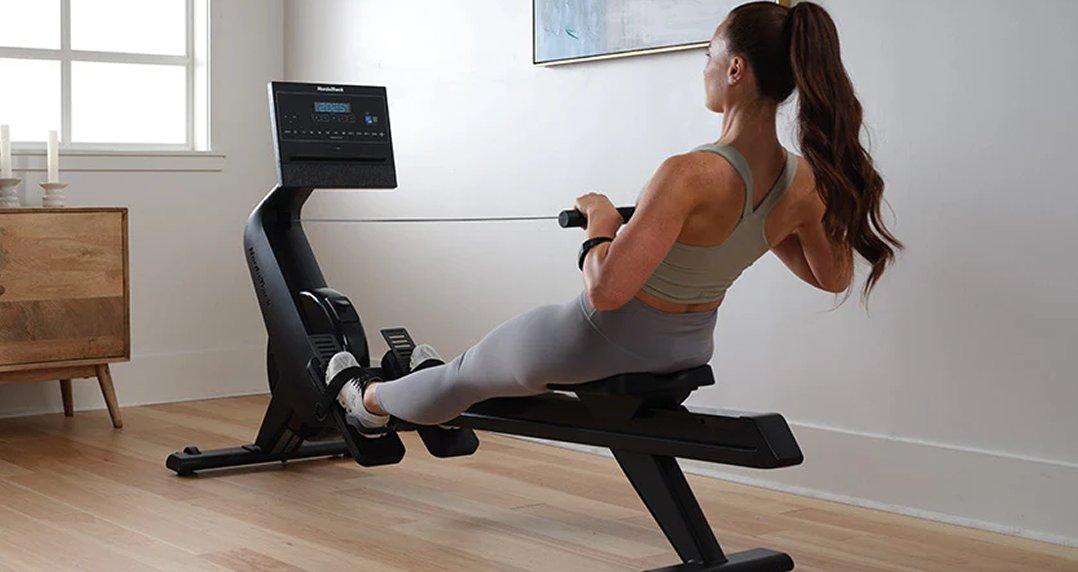 a woman is using a rowing machine in a living room