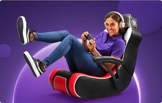 A Currys colleague in a gaming chair holding a gaming console controller