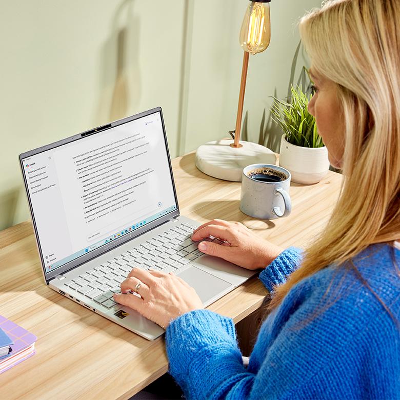 a woman in a blue sweater is typing on a laptop