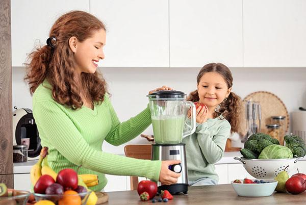 a woman and child in a kitchen with a blender