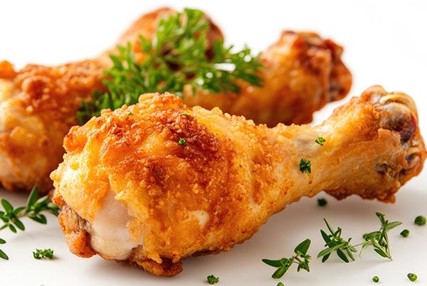 two chicken legs are sitting on a white surface with herbs