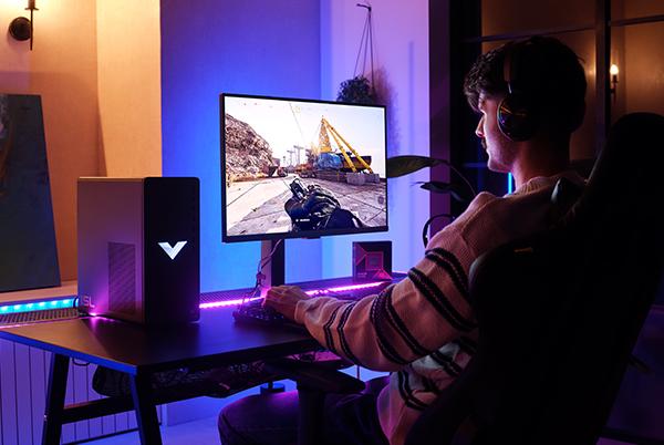 a man sitting at a desk playing a video game on a computer