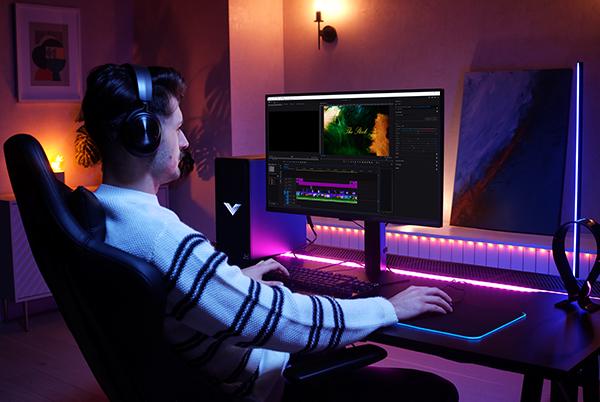 a man in headphones sitting at a desk with a computer monitor