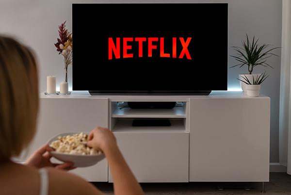 a woman eating popcorn while watching netflix on a tv