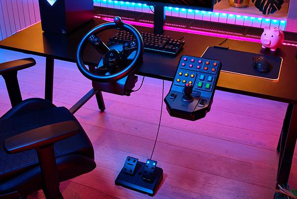 a desk with a steering wheel and a computer monitor