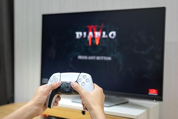 a person holding a video game controller in front of a television