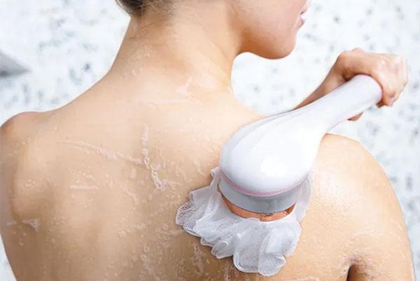 a woman using a shower head to clean her back