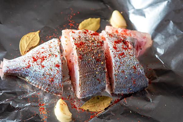 a fish is on a piece of foil with spices and herbs