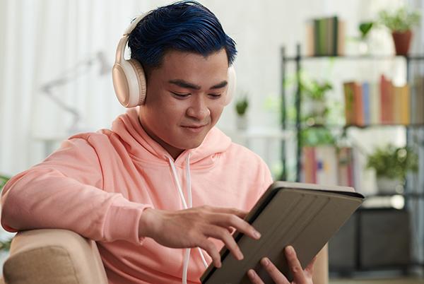a man in pink sweatshirt with headphones on a tablet