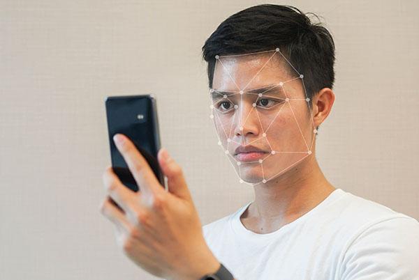 a man holding a cell phone with a facial recognition system