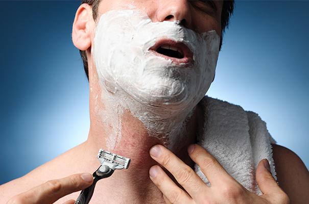 a man shaving his face with a razor and towel