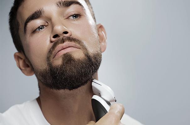 a man with a beard shaving his face with an electric shaver