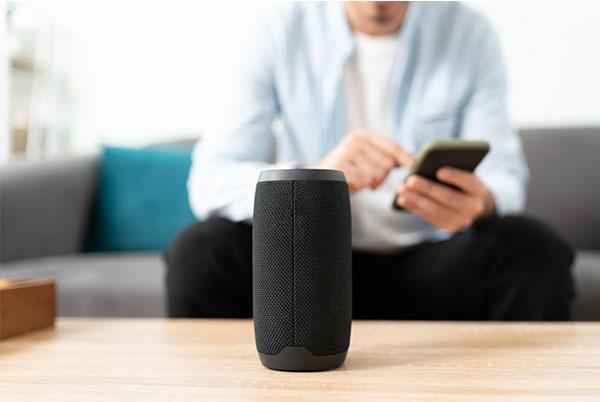 a man sitting on a couch with a smart speaker in front of him