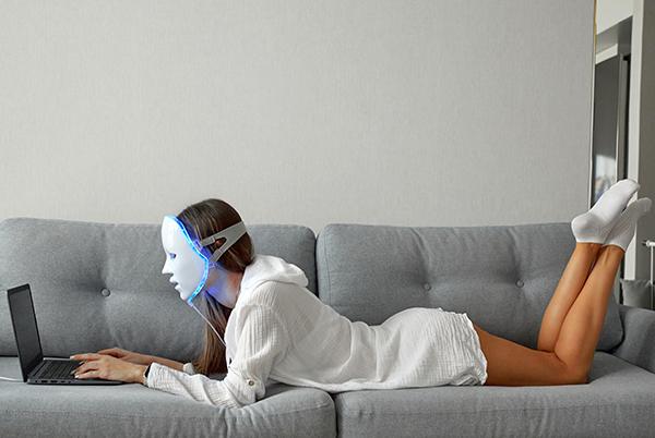 a woman laying on a couch with a mask on her face