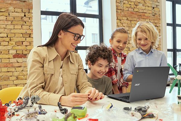 a woman and three children looking at a laptop computer