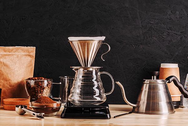 a coffee maker, coffee beans, and a coffee grinder sit on a table