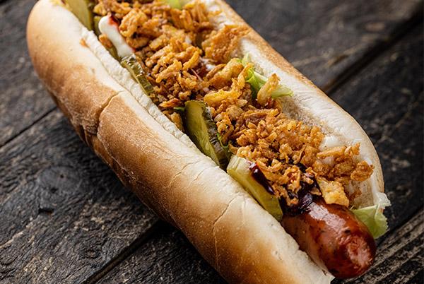 a hot dog with toppings on a wooden table