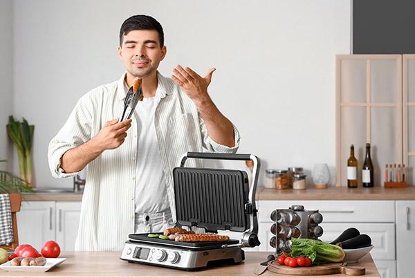 a man standing in a kitchen with a grill and a knife