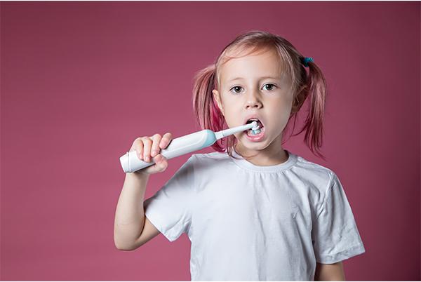 Child cleaning teeth with an electric toothbrush