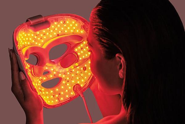 a Shark LED mask with a light on it next to a remote