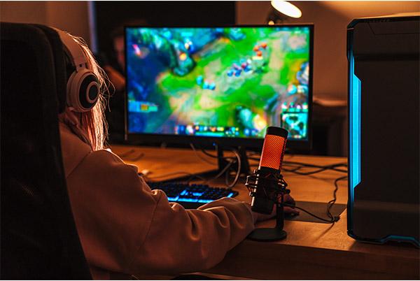 a person sitting at a desk with headphones on playing a video game