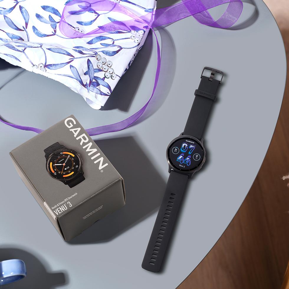 a table with a coffee cup and a Garmin Venu 3 watch on it
