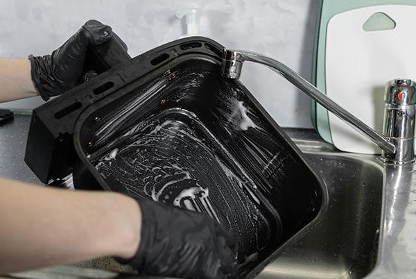 a person washing a pan in a sink with a sponge