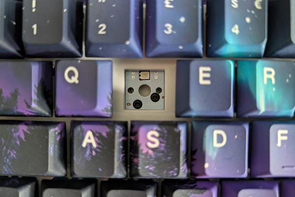 a close up of a computer keyboard with a hole in it