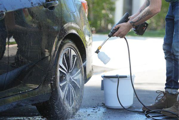 a man using a Drew & Cole Jet Hawk Pressure Washer to clean a car