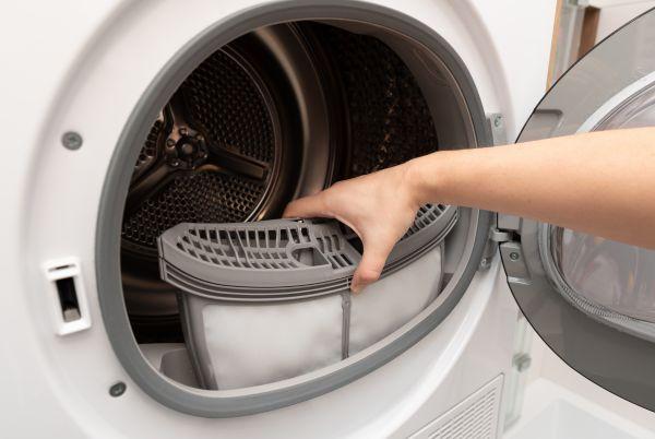 a person opening the door of a tumble dryer to take out lint collection tray