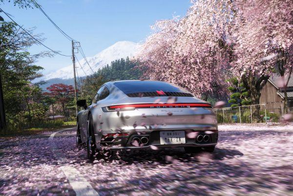 A car from Forza Horizon 6 driving down a road with cherry blossoms falling from the trees