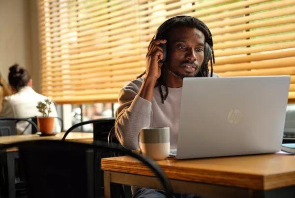 a man sitting at a table with a HP Omnibook laptop and headphones on