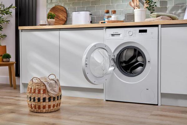 a Bosch Series 2 washing machine sitting in a kitchen with a basket next to it