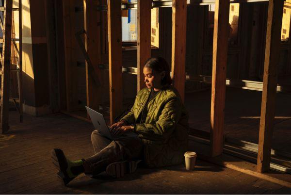 a woman sitting on the floor with an Apple MacBook Pro