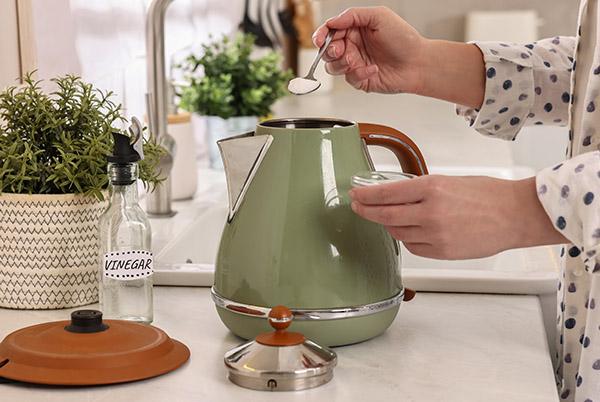 a woman pouring a drink from a kettle on a counter
