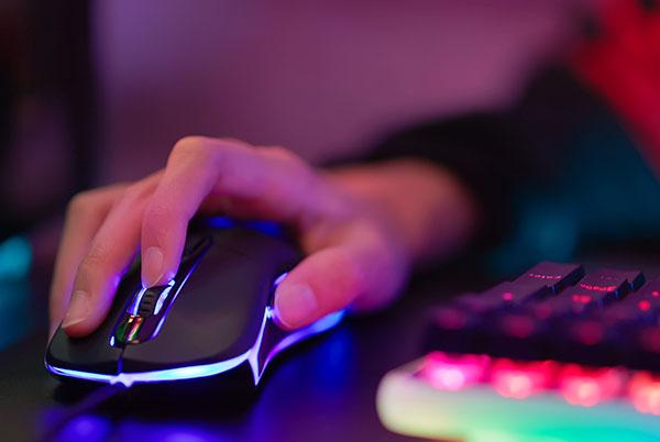 a person's hand on a computer mouse with a glowing keyboard