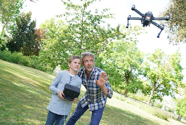 a man and boy standing in a field with a drone