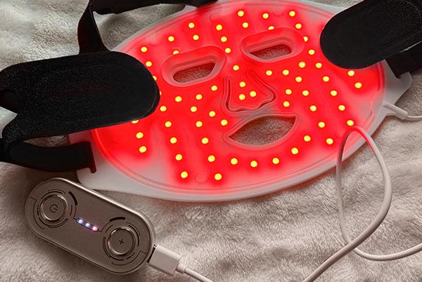 a red led lighted mask with a remote control attached to it