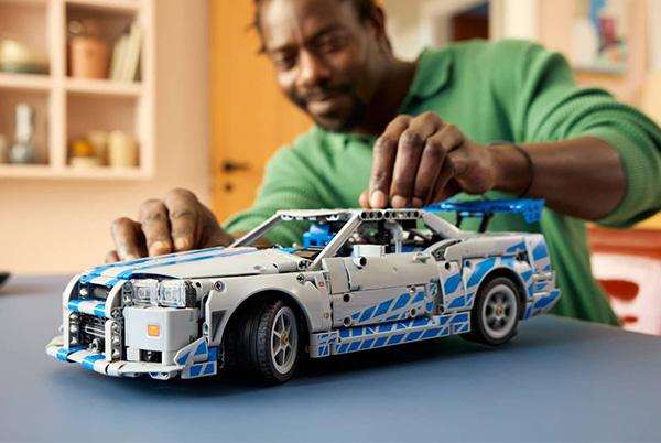 a man building a lego car with a green shirt on