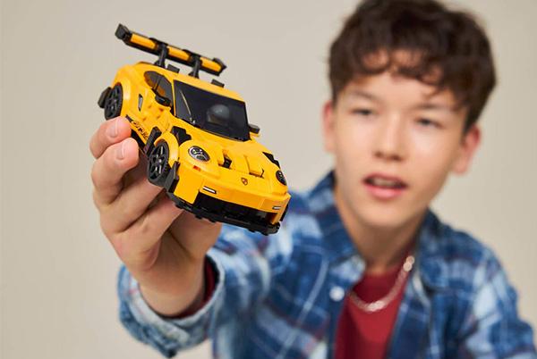 a young boy holding a yellow toy car in his hand