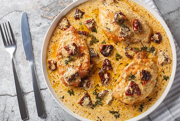 a plate of chicken in cream sauce with a fork and knife