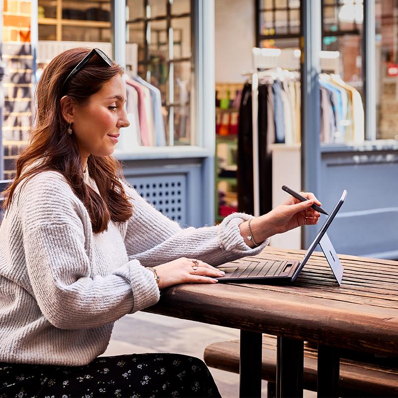 a woman sitting at a table with a laptop and pen